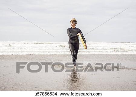 Picture - Mature female bodyboarder paddling on Devon coast, UK. Fotosearch