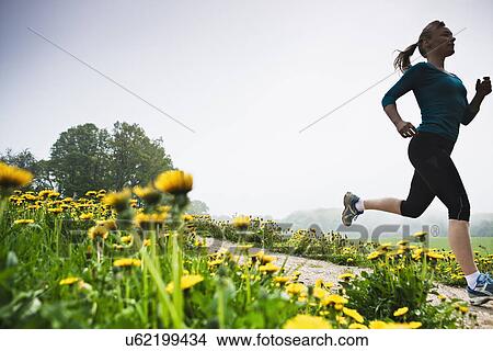 Picture - Mature woman running in countryside. Fotosearch