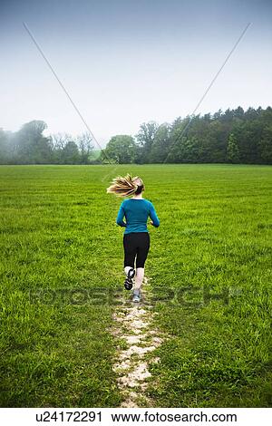 Stock Image - Mature woman running in countryside. Fotosearch