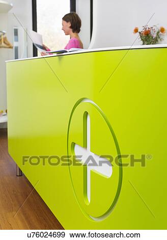 Stock Photo - Medical reception desk with woman working in background. Fotosearch