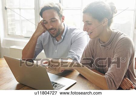 Stock Photo - Mid adult couple using laptop. Fotosearch