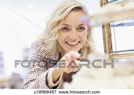 Stock Photo - Mid adult female pointing at cake display in cafe. Fotosearch