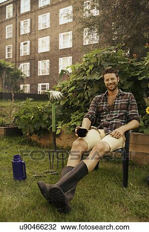Mid adult man taking a break on council estate allotment View Large Photo Image Stock Image - Mid adult man taking a break on council estate allotment. Fotosearch
