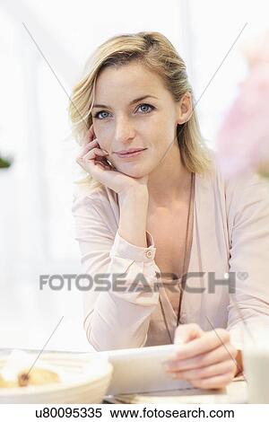 Stock Photography - Mid adult woman holding digital tablet in cafe. Fotosearch