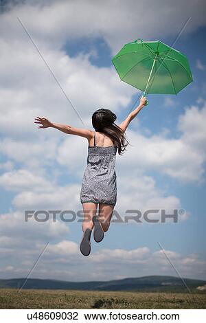 Mid adult woman holding green umbrella, jumping View Large Photo Image Stock Image - Mid adult woman holding green umbrella, jumping. Fotosearch