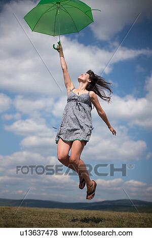 Mid adult woman holding green umbrella, jumping View Large Photo Image Stock Photo - Mid adult woman holding green umbrella, jumping. Fotosearch