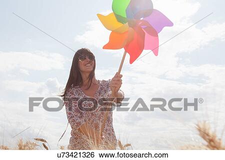 Stock Photograph - Mid adult woman holding windmill. Fotosearch