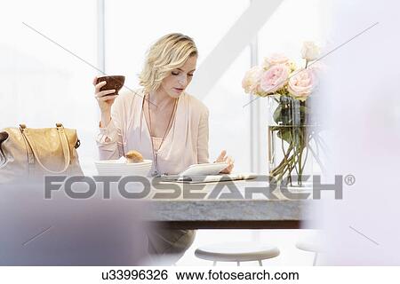 Mid adult woman looking at digital tablet in cafe View Large Photo Image Stock Photograph - Mid adult woman looking at digital tablet in cafe. Fotosearch