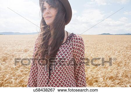 Mid adult woman standing in wheat field View Large Photo Image Stock Photo - Mid adult woman standing in wheat field. Fotosearch