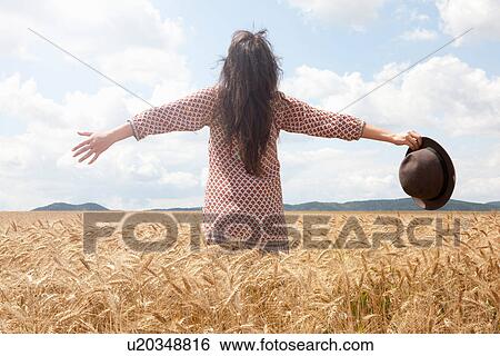 Mid adult woman standing in wheat field with arms out wide View Large Photo Image Stock Photograph - Mid adult woman standing in wheat field with arms out wide. Fotosearch
