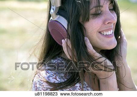 Mid adult woman wearing headphones with eyes closed View Large Photo Image Stock Image - Mid adult woman wearing headphones with eyes closed. Fotosearch