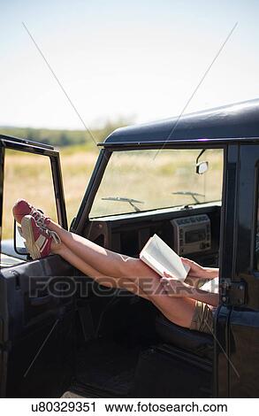 Mid adult women sitting in car reading book View Large Photo Image Stock Image - Mid adult women sitting in car reading book. Fotosearch