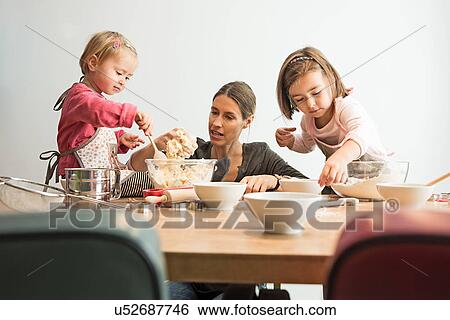 Stock Photograph - Mother and children baking, mixing batter. Fotosearch