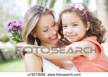 Mother and daughter hugging, holding bunch of flowers View Large Photo Image Stock Photograph - Mother and daughter hugging, holding bunch of flowers. Fotosearch