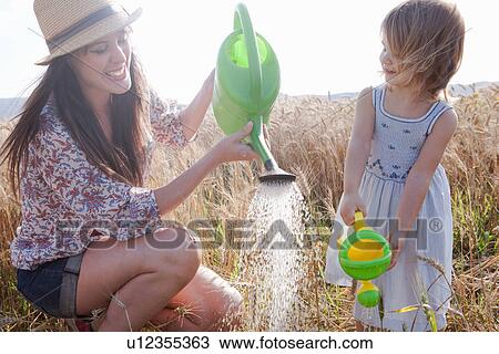 Mother and daughter in wheat field with watering cans View Large Photo Image Stock Image - Mother and daughter in wheat field with watering cans. Fotosearch