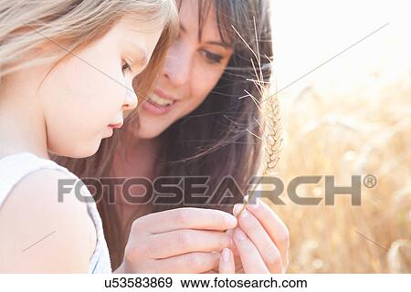 Stock Photo - Mother and daughter looking at grain of wheat. Fotosearch