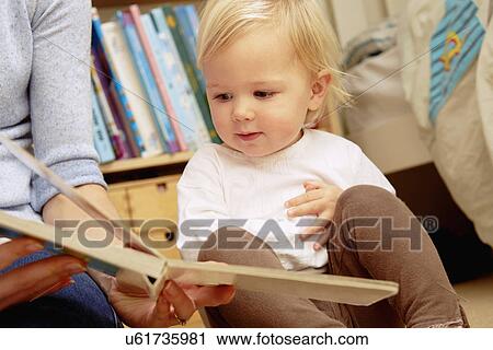 Mother reading picture book with baby daughter View Large Photo Image Stock Image - Mother reading picture book with baby daughter. Fotosearch