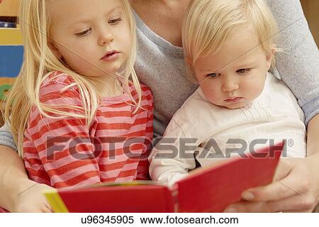 Mother reading picture book with two daughters View Large Photo Image Stock Photography - Mother reading picture book with two daughters. Fotosearch