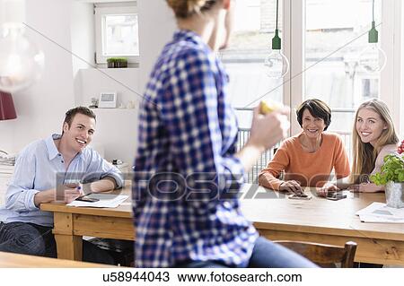 Mother with grown up children at table, young woman in foreground View Large Photo Image Stock Image - Mother with grown up children at table, young woman in foreground. Fotosearch