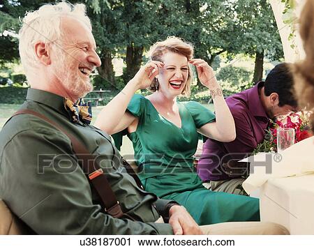 Stock Image - Newly married couple with parents laughing at wedding reception. Fotosearch