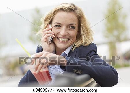 Stock Photo - Office worker having lunch break on park bench. Fotosearch