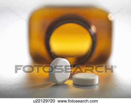 Stock Image - Pain killers pouring from brown medicine bottle. Fotosearch