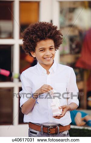 Portrait of boy eating confectionary outside shop View Large Photo Image Stock Image - Portrait of boy eating confectionary outside shop. Fotosearch