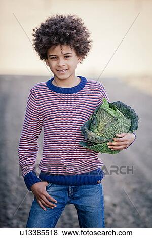 Stock Photo - Portrait of boy in field holding cabbage. Fotosearch