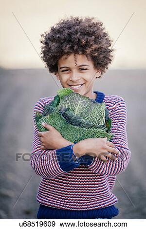 Portrait of boy in field hugging cabbage View Large Photo Image Stock Photo - Portrait of boy in field hugging cabbage. Fotosearch