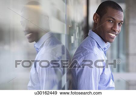 Stock Photo - Portrait of businessman leaning against wall. Fotosearch