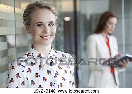 Portrait of businesswoman with colleague in background View Large Photo Image Stock Image - Portrait of businesswoman with colleague in background. Fotosearch