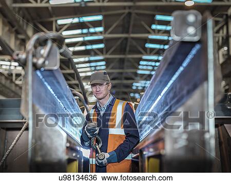 Stock Photograph - Portrait of engineer fixing lifting straps in factory. Fotosearch