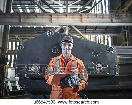 Portrait of engineer holding clipboard in factory View Large Photo Image Stock Image - Portrait of engineer holding clipboard in factory. Fotosearch