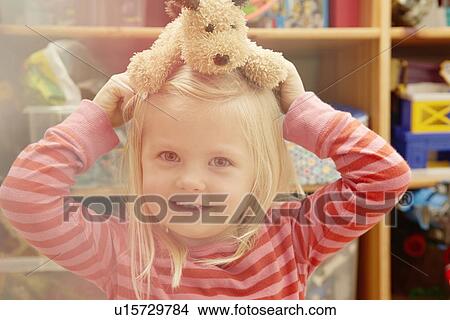 Picture - Portrait of girl with teddy bear on head. Fotosearch