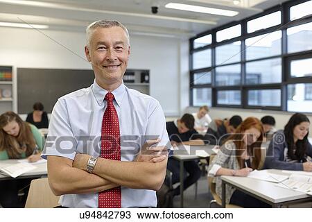 Stock Image - Portrait of mature male teacher in classroom. Fotosearch