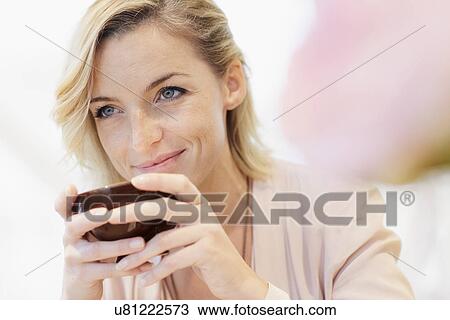 Stock Image - Portrait of mid adult woman with cup of coffee. Fotosearch