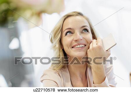 Stock Photo - Portrait of mid adult woman with mobile daydreaming. Fotosearch