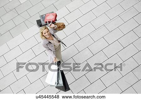 Stock Photo - Portrait of mid adult woman with abundance of shopping bags. Fotosearch