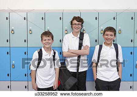 Stock Image - Portrait of three boys next to school lockers. Fotosearch