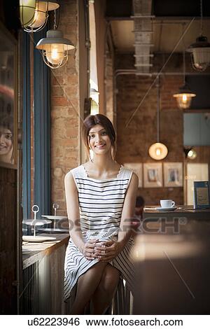 Stock Photograph - Portrait of woman in restaurant wearing striped dress. Fotosearch