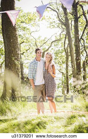 Stock Image - Portrait of young couple standing in forest. Fotosearch