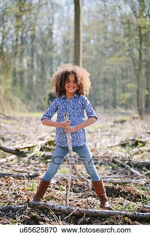 Portrait of young girl in woods holding a stick View Large Photo Image Stock Image - Portrait of young girl in woods holding a stick. Fotosearch