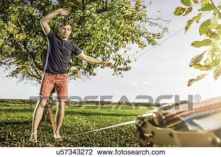 Stock Image - Portrait of young man balanced on slackline. Fotosearch
