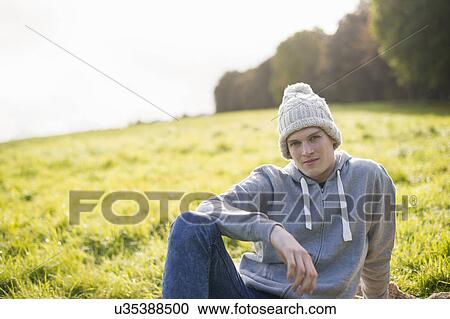 Portrait of young man sitting on grass wearing knit hat View Large Photo Image Stock Image - Portrait of young man sitting on grass wearing knit hat. Fotosearch