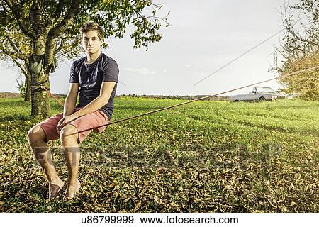 Portrait of young man sitting on slackline View Large Photo Image Stock Photo - Portrait of young man sitting on slackline. Fotosearch