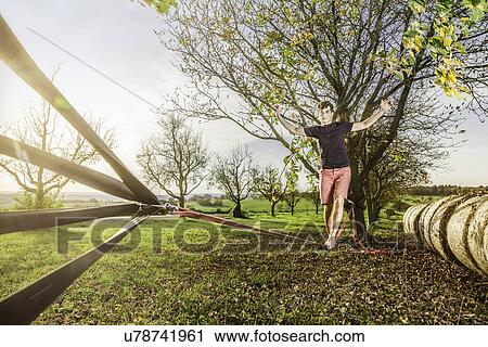 Stock Image - Portrait of young man walking on slackline. Fotosearch