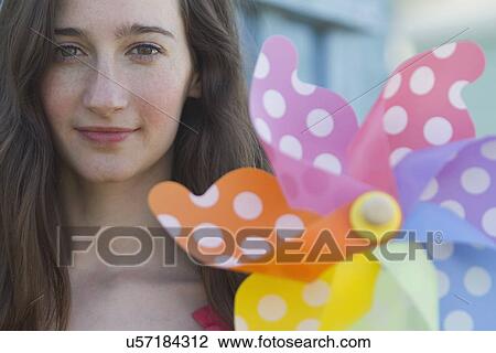 Portrait of young woman holding paper windmill View Large Photo Image Stock Image - Portrait of young woman holding paper windmill. Fotosearch
