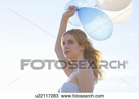 Portrait of young woman holding up balloons View Large Photo Image Stock Image - Portrait of young woman holding up balloons. Fotosearch