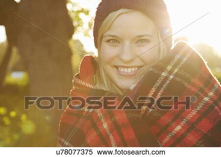 Portrait of young woman in park, tartan picnic blanket around shoulders View Large Photo Image Stock Photography - Portrait of young woman in park, tartan picnic blanket around shoulders. Fotosearch