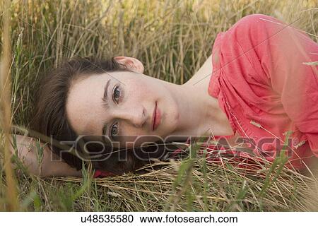 Portrait of young woman lying on grass View Large Photo Image Stock Image - Portrait of young woman lying on grass. Fotosearch